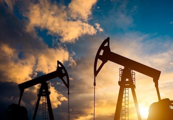 Oil field site, in the evening, oil pumps are running, The oil pump and the beautiful sunset reflected in the water, the silhouette of the beam pumping unit in the evening.